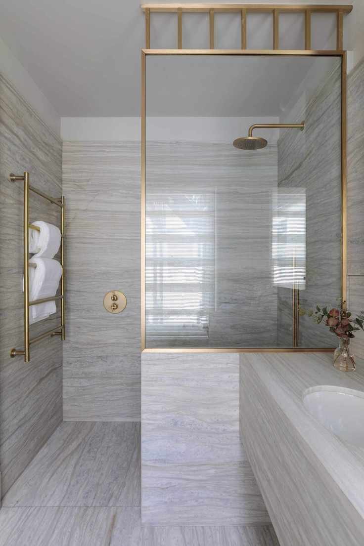 A neutral bathroom featuring stone and gold fixtures
