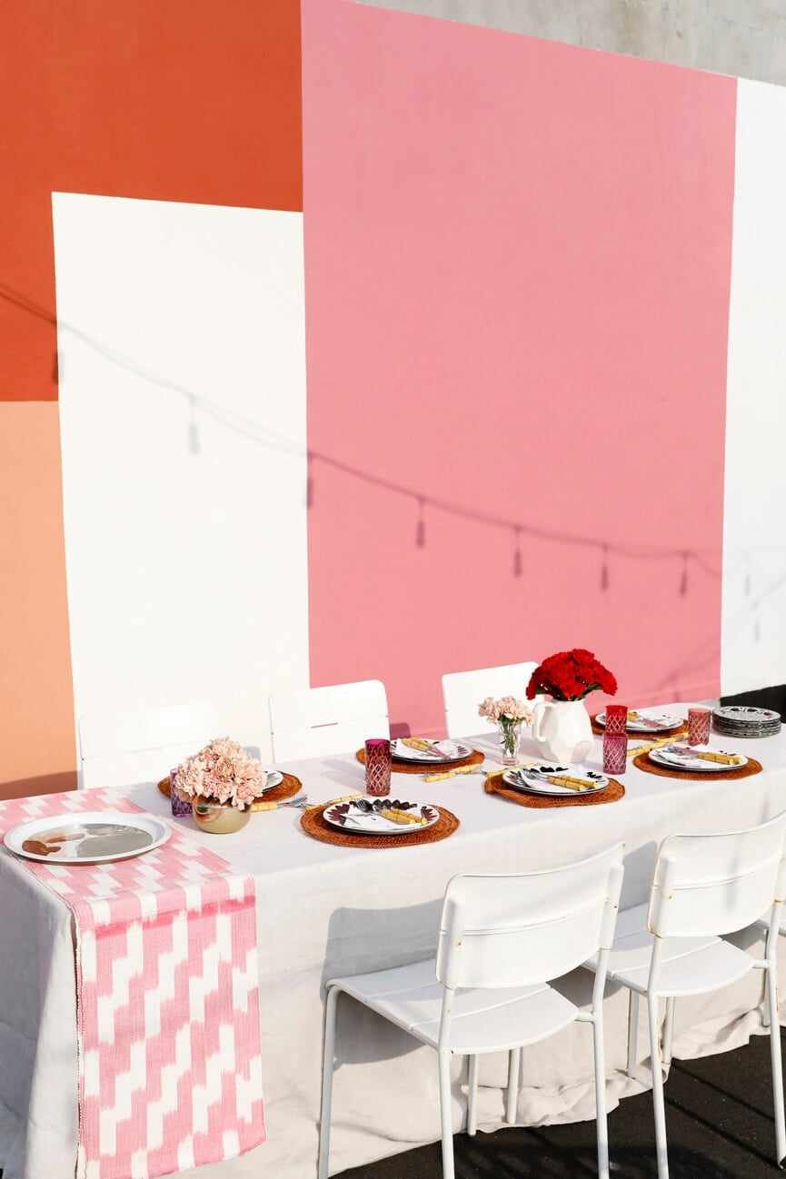 dinner party table decor on a new york city rooftop with white table and pink decor