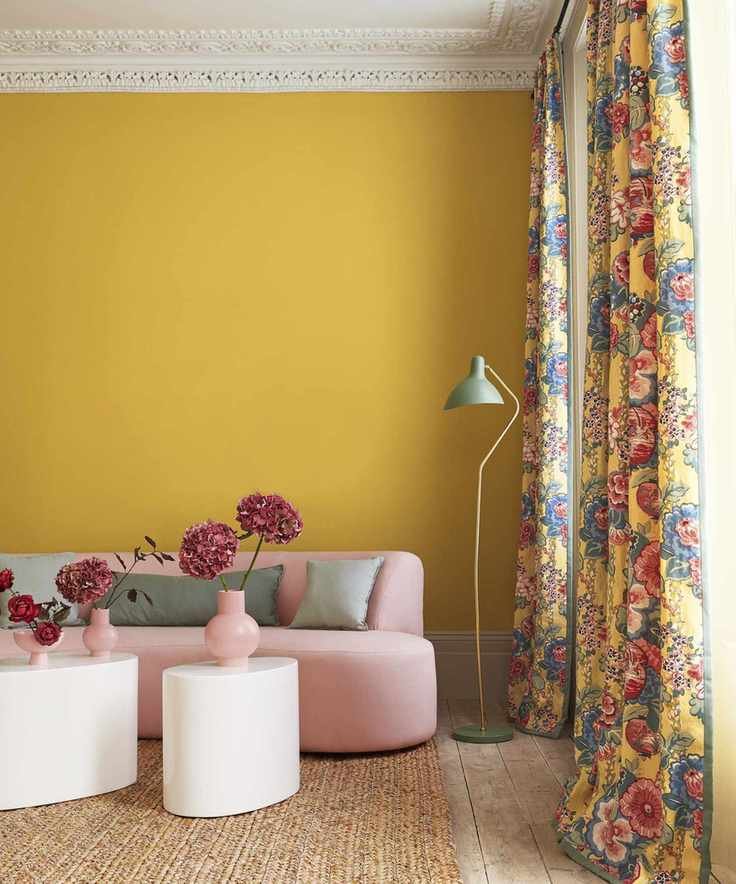 A living room curtain idea with yellow walls, pink sofa and yellow floral curtains