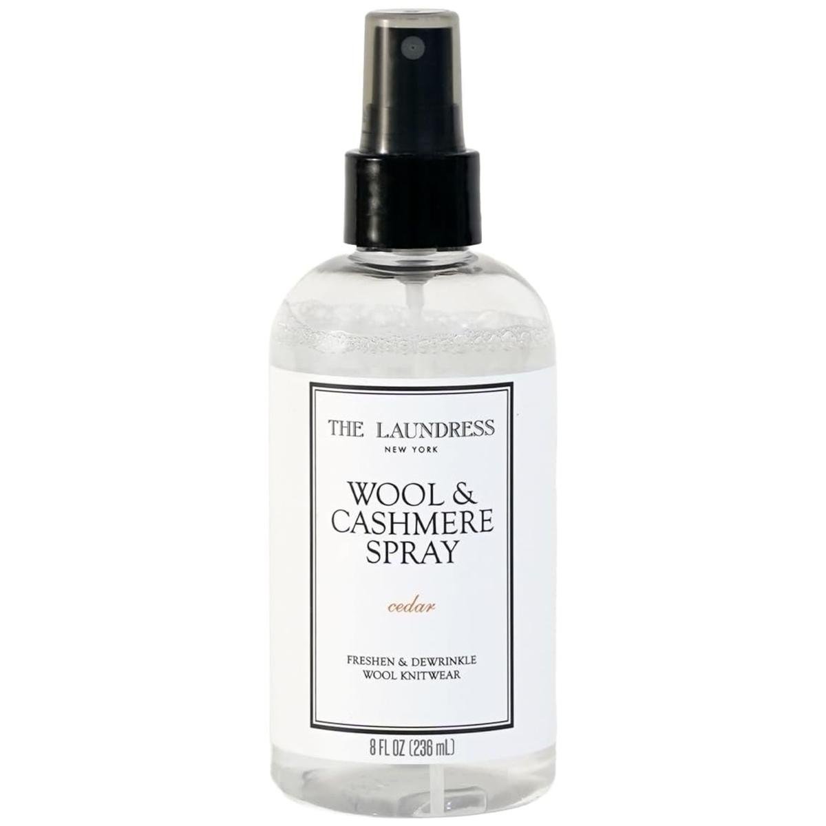 A clear plastic bottle of The Laundress Wool &amp;amp; Cashmere spray with a white and black label, and a black spray lid