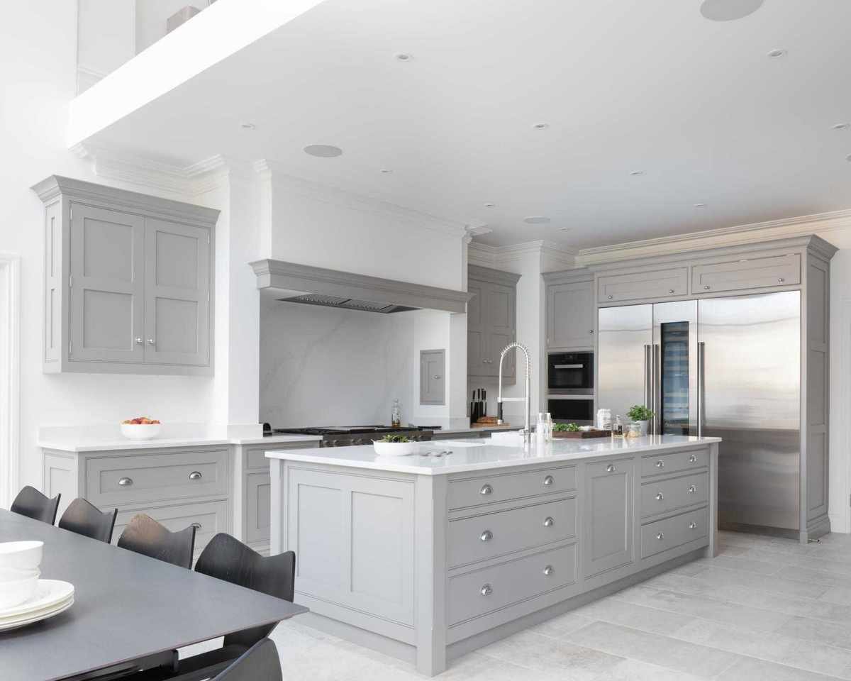A white and gray open plan kitchen with double height ceiling.