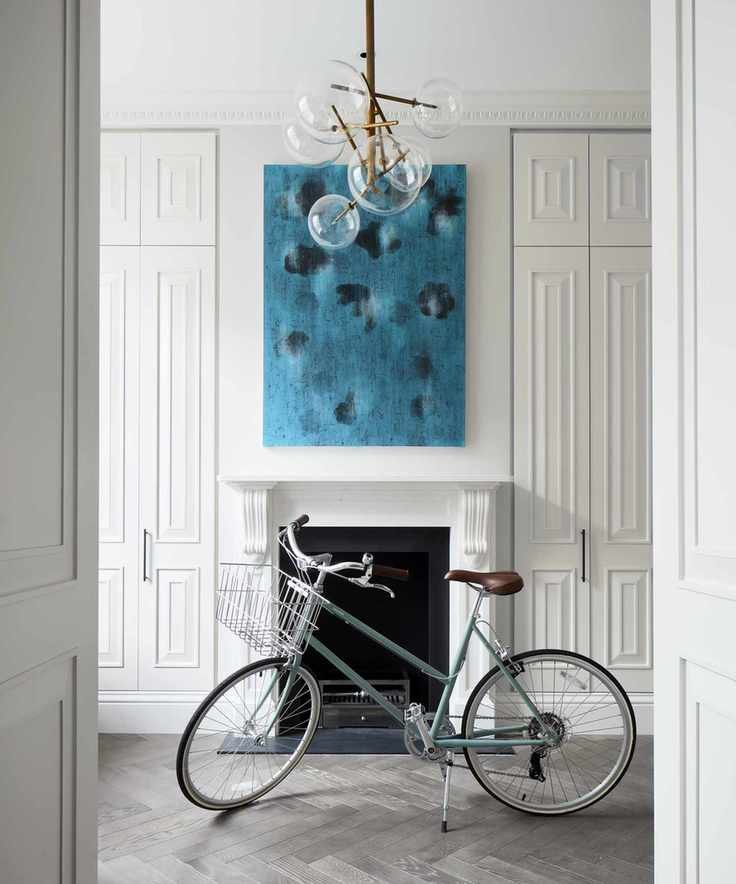 A white entrance hall with floor-to-ceiling storage cupboards and large blue artwork over the fireplace