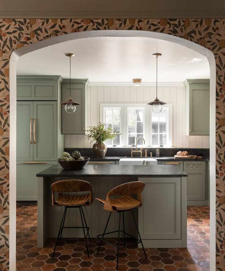 Sage green painted kitchen cabinets in a stylish home with white walls and terracotta flooring.