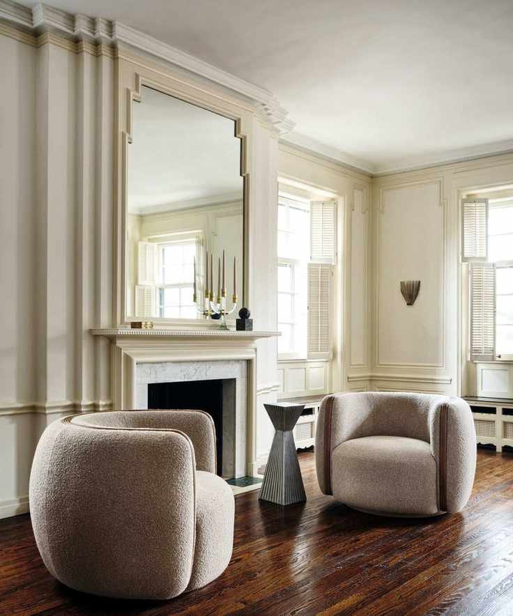 a sitting room with two chairs, a geometrically shaped drink table, and a fireplace