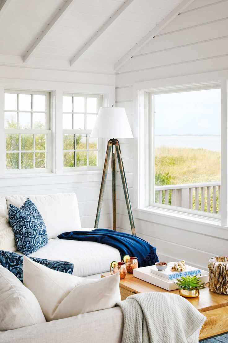 white sofas and chairs facing sea view across dunes from beach house with outside deck tripod standard lamp