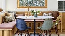 Small dining room ideas with a white oak corner bench, round table and colored chairs