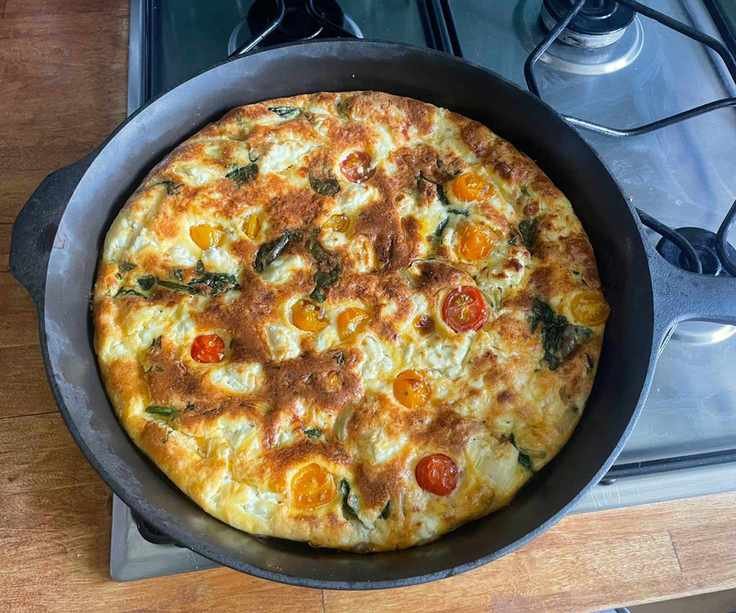 Field company skillet on a gas stove with a cooked frittata inside.