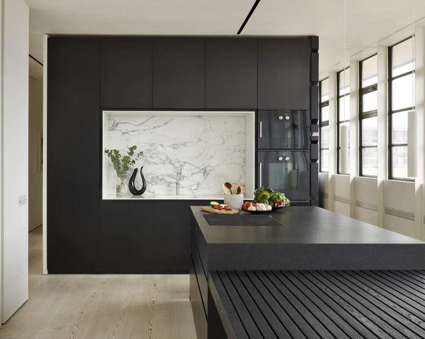 A black kitchen idea with a white marble alcove surrounded by black cabinetry and a black wooden island