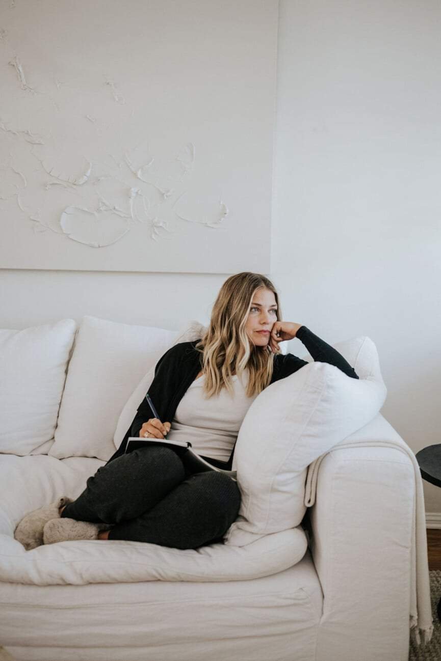 Woman journaling on couch.