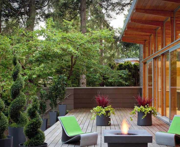 A raised deck area with green chairs and a fire pit