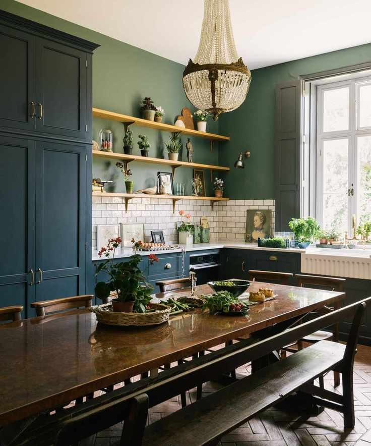 navy devol kitchen with green walls and a long kitchen table with a large chandelier