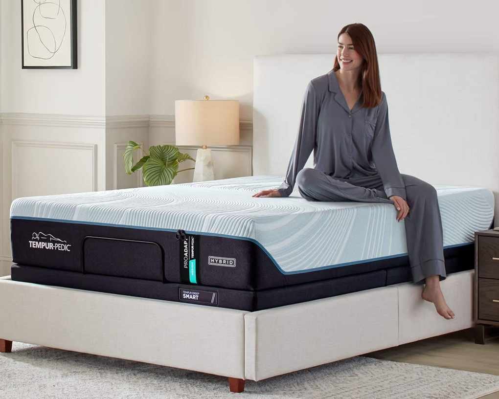 A woman sitting on the Tempur-Pedic Pro-Adapt mattress.