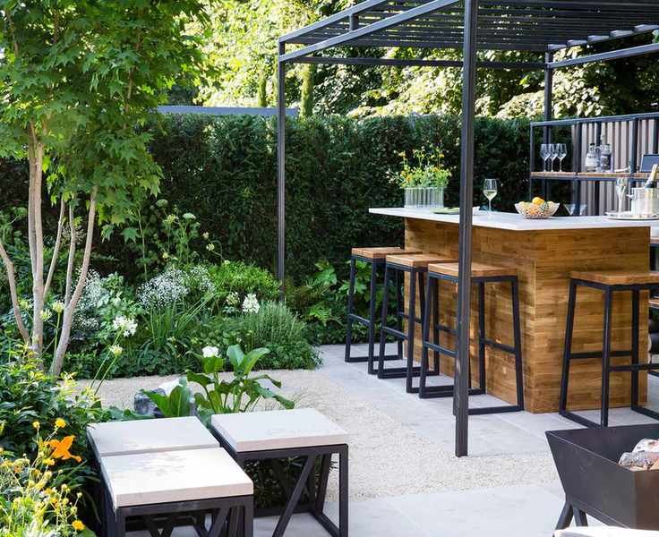 A modern garden bar design surrounded by flower beds in a stylish outdoor setting.