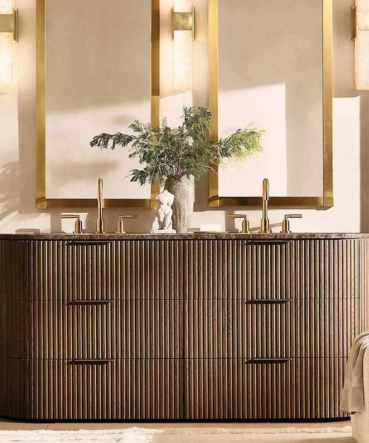 A neutral bathroom with a dark fluted wood vanity and gold mirrors