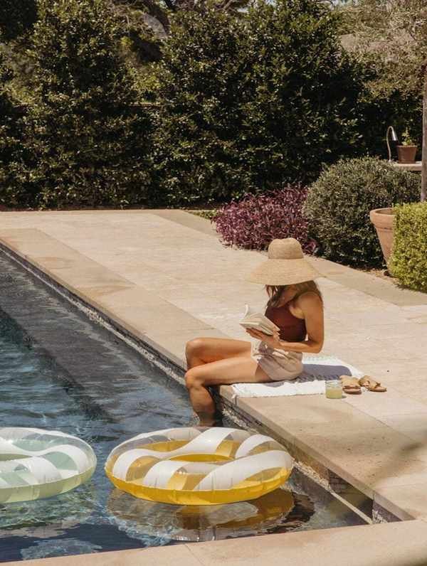 Woman relaxing by the pool in July.
