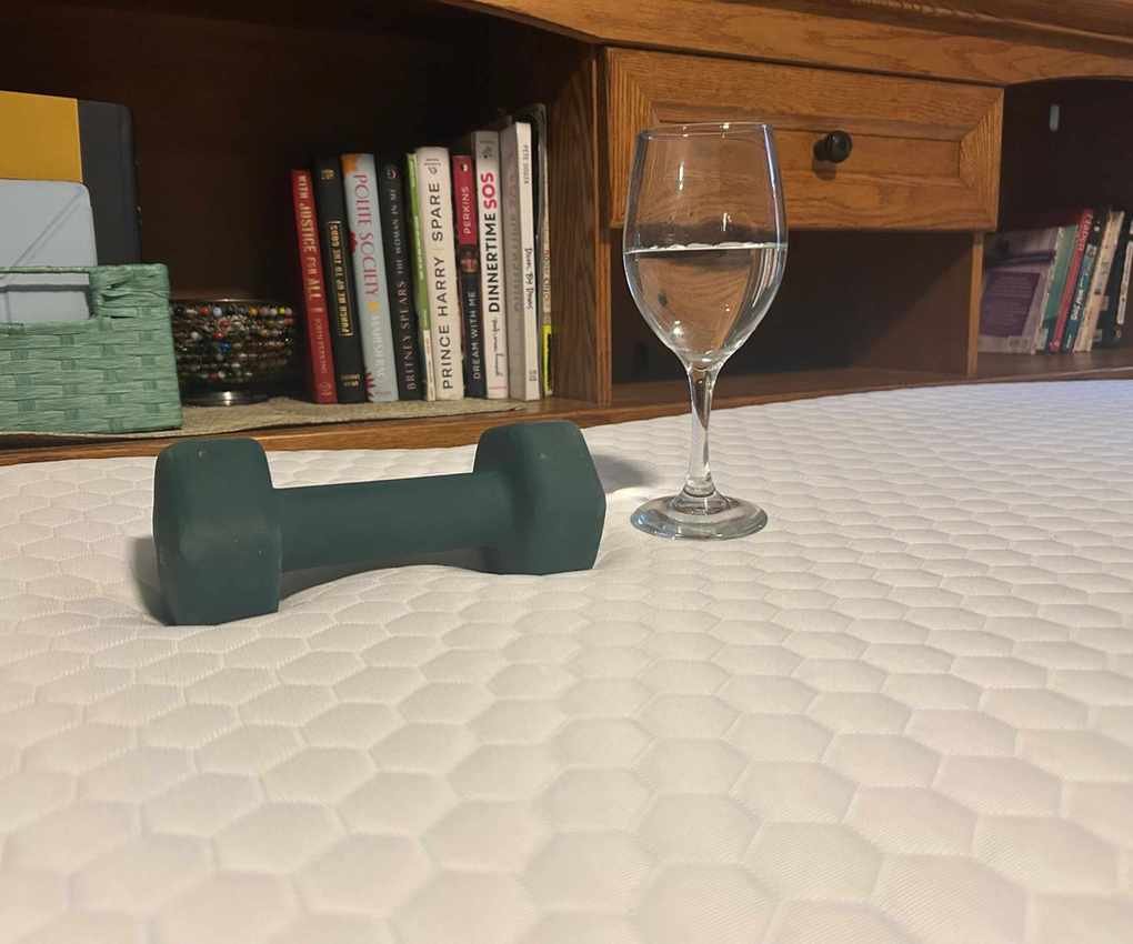 A wine glass and a dumbbell resting on the Helix ErgoAlign Mattress Topper.