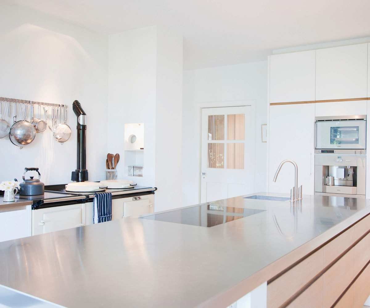 Modern kitchen with stainless steel counters, hanging pans and a classic style kettle on the stove