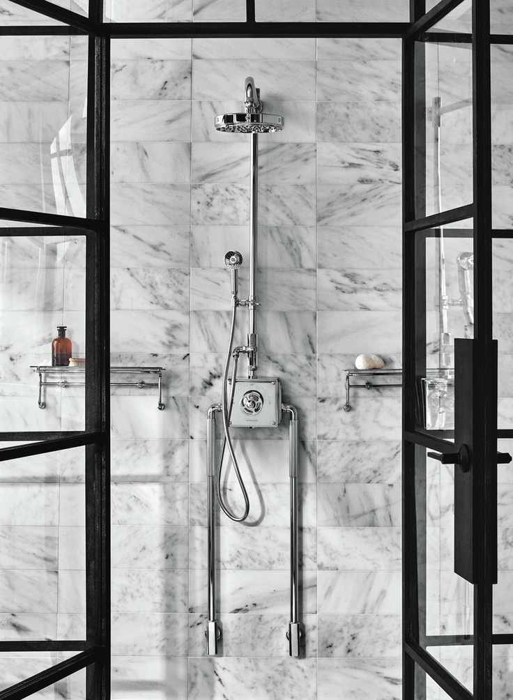 marble tiled shower wall with chrome shower and black framed glass shower doors