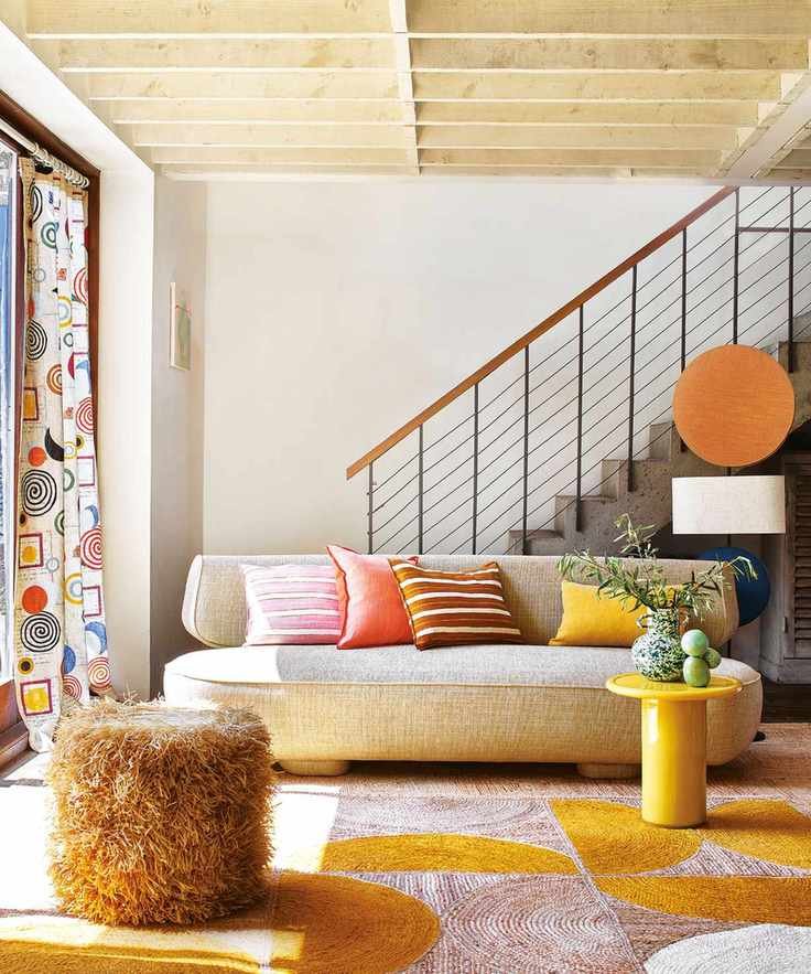 Bright, modern living room with curvaceous cream sofa, yellow side table, colorful rug and cushions