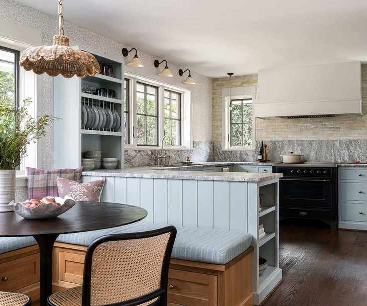 A blue peninsula kitchen with grey and white marble countertops