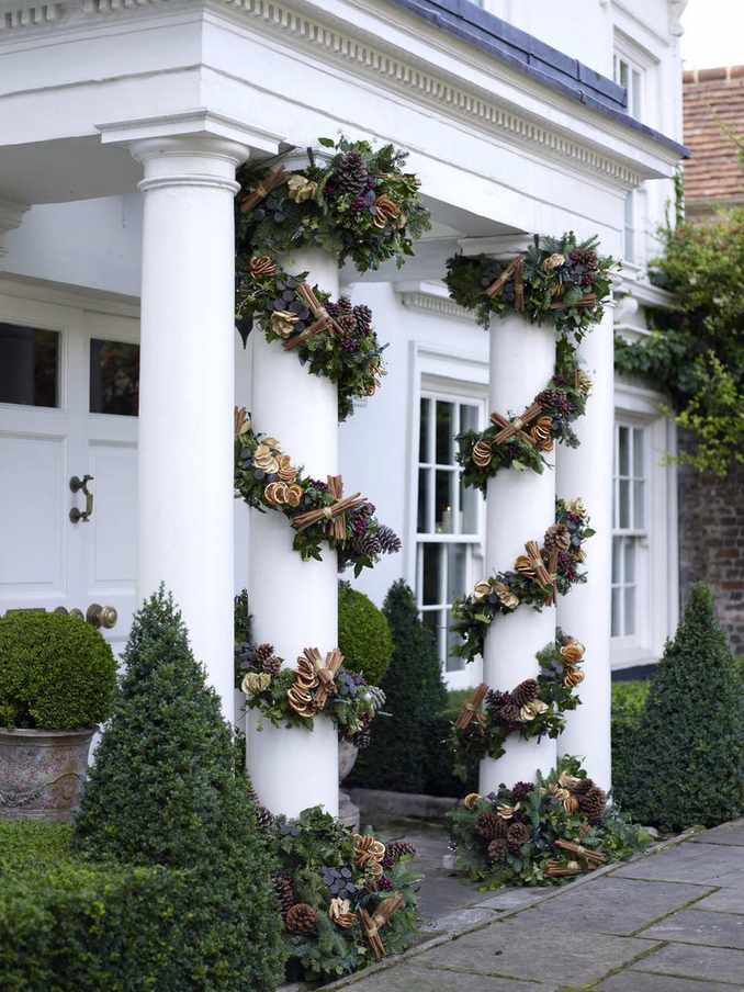 Front porch pillars wrapped in pine cone garland