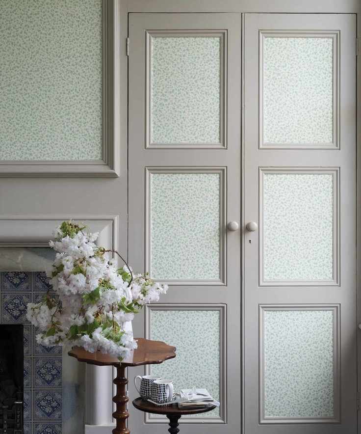 An example of how to hang wallpaper on gray cupboard doors, beside a traditional dove gray fireplace.