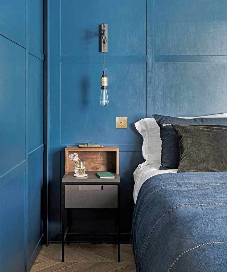 Bedroom with blue paneling and denim bedding, complemented by wooden decor