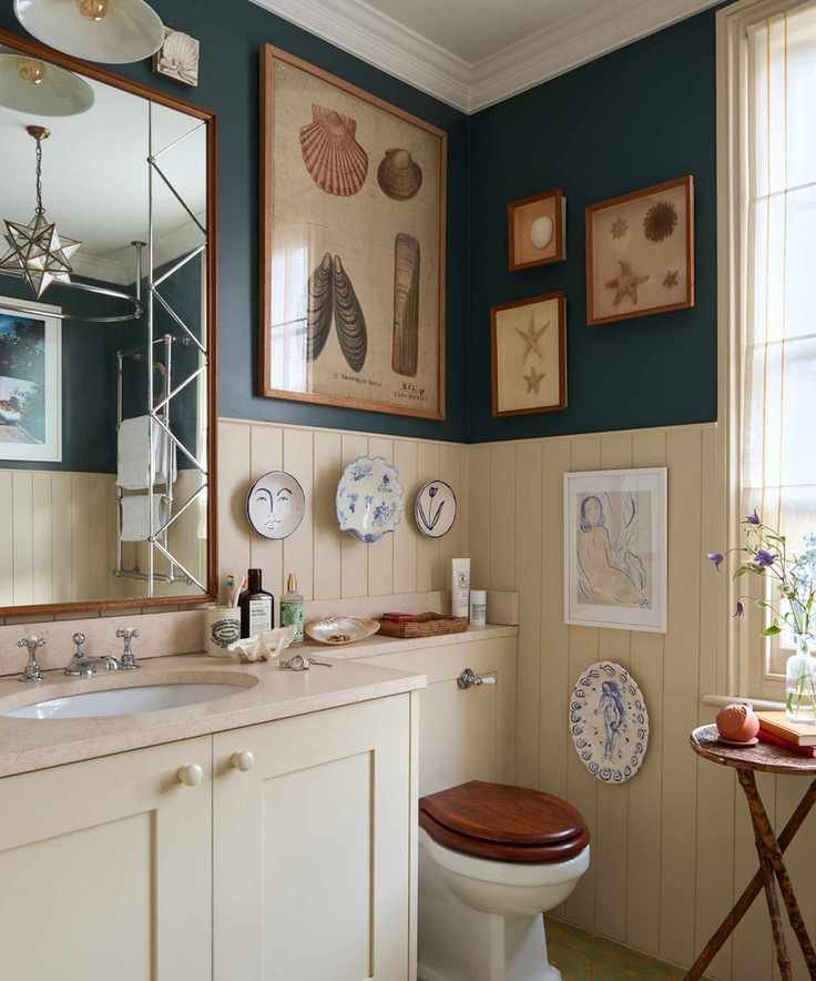 Cream wood panelled bathroom with vintage shell prints, ceramic plates on walls and large mirror