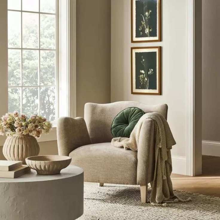 A gray armchair with a circular green pillow and white throw blanket