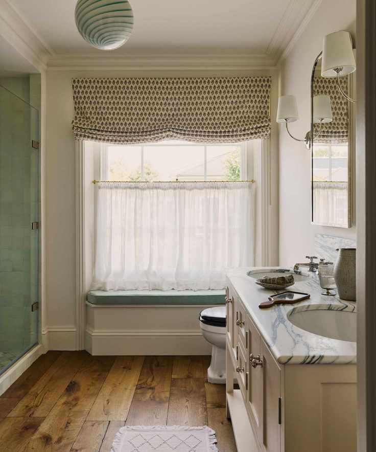 Bright bathroom with a blue window seat and sheer cafe curtains