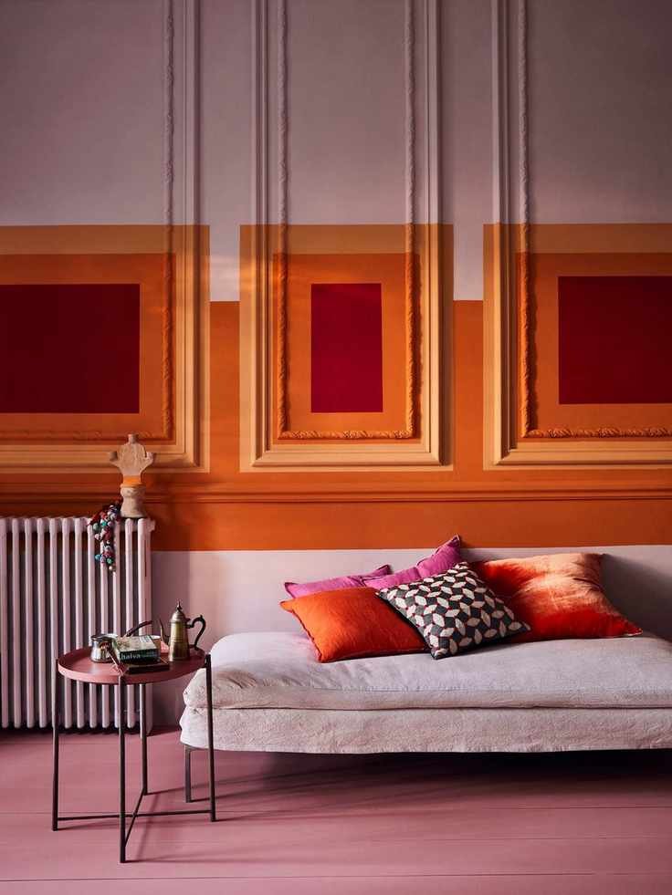 modern living room with pink sofa, pink painted floor, contemporary wall mural painted in colour blocks