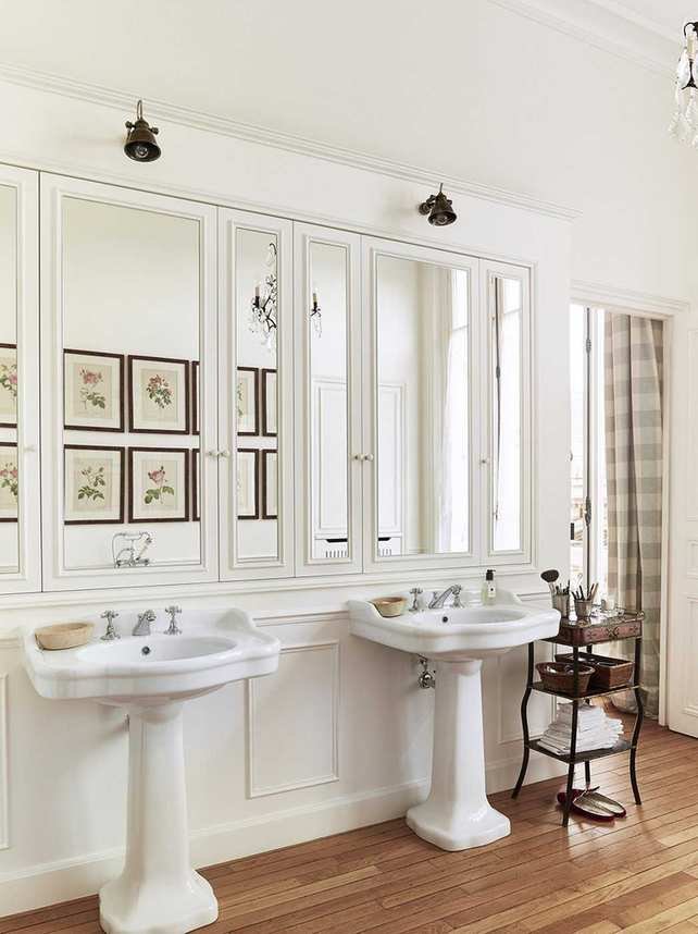 A bathroom with mirrored panels over double sinks