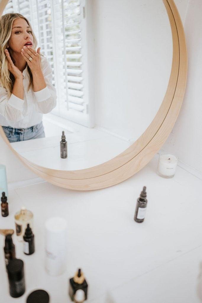 Janessa Leoné applying skincare in mirror_tamanu oil for skin
