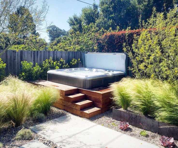 hot tub on a patio surrounded by ornamental grasses and planting