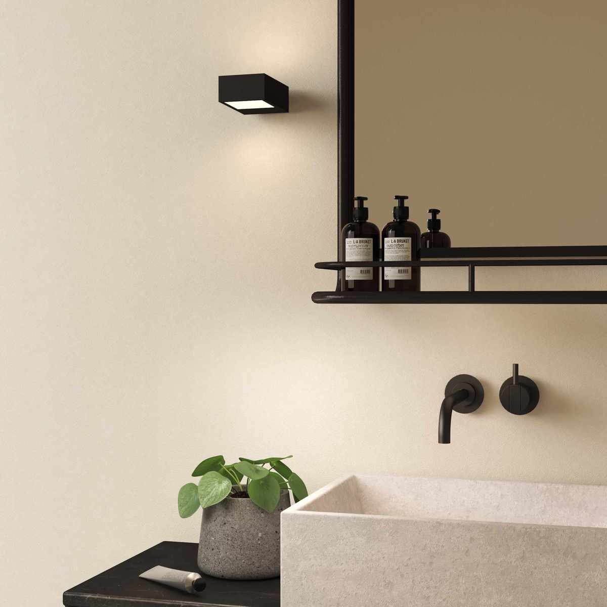 Black wall light beside mirror in bathroom with sink below and wall mounted faucet