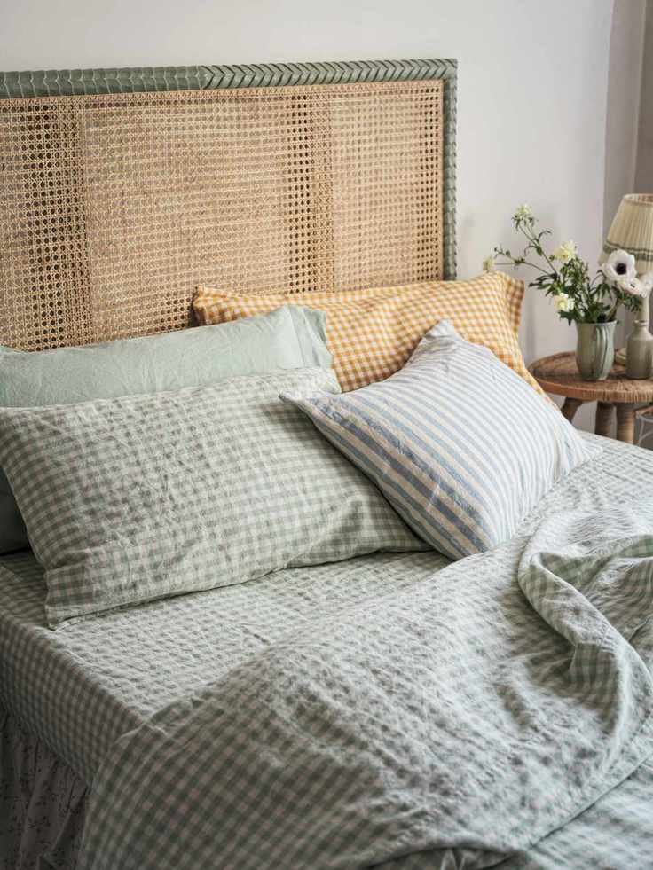 A bed with a cane headboard and green and white checkered bedding