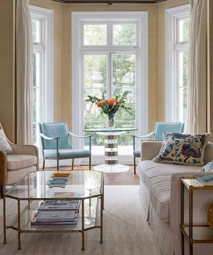 Beige living room with textured wallpaper, vibrant blue chairs, and large windows.