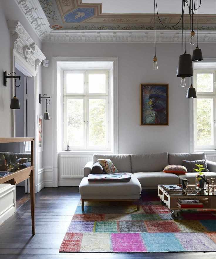 A white living room, multicolored rug and beige sofa with a variety of living room lighting.