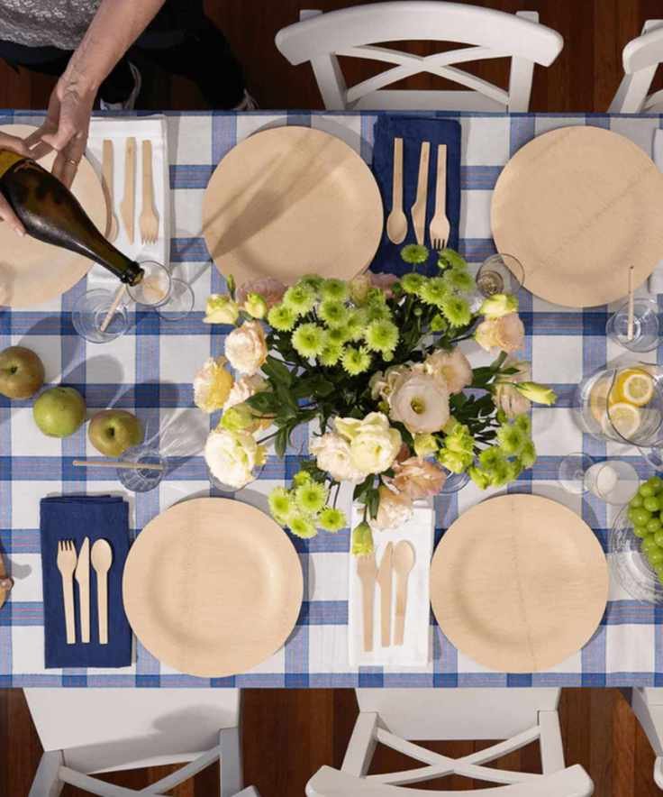Table set with gingham tablecloth, green and white flowers and bambu plates
