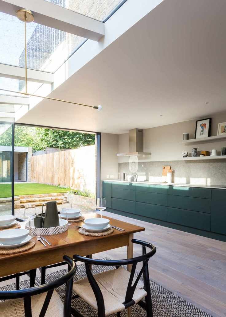 white kitchen with green cabinetry, wooden floor, dining table and chairs, glazed ceiling, crittall doors, open shelving