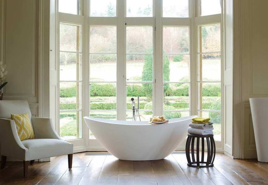 A bright bathroom with a tub by a large window