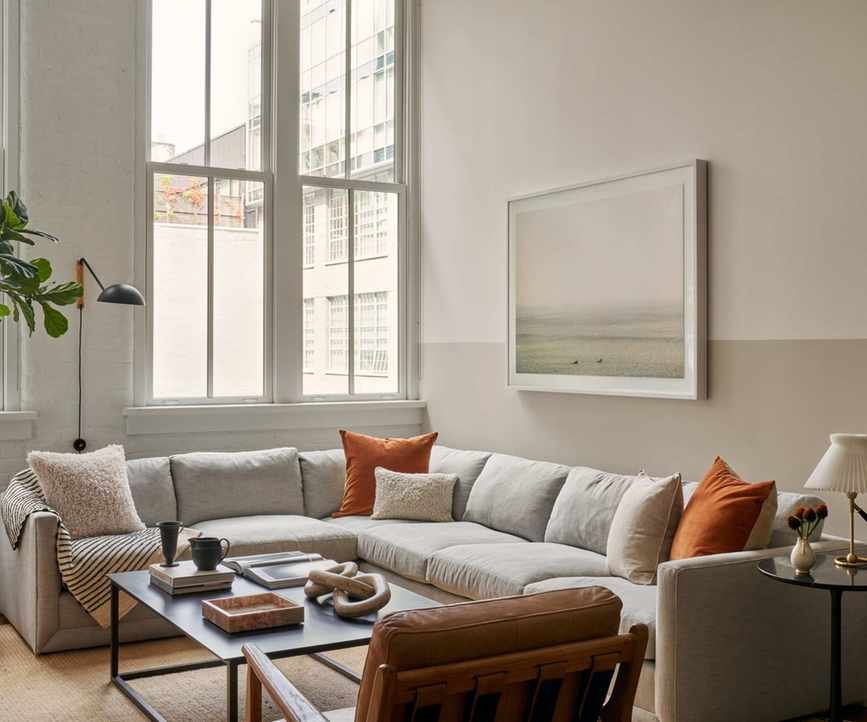 tall ceiling living room modern apartment with corner couch and orange accents