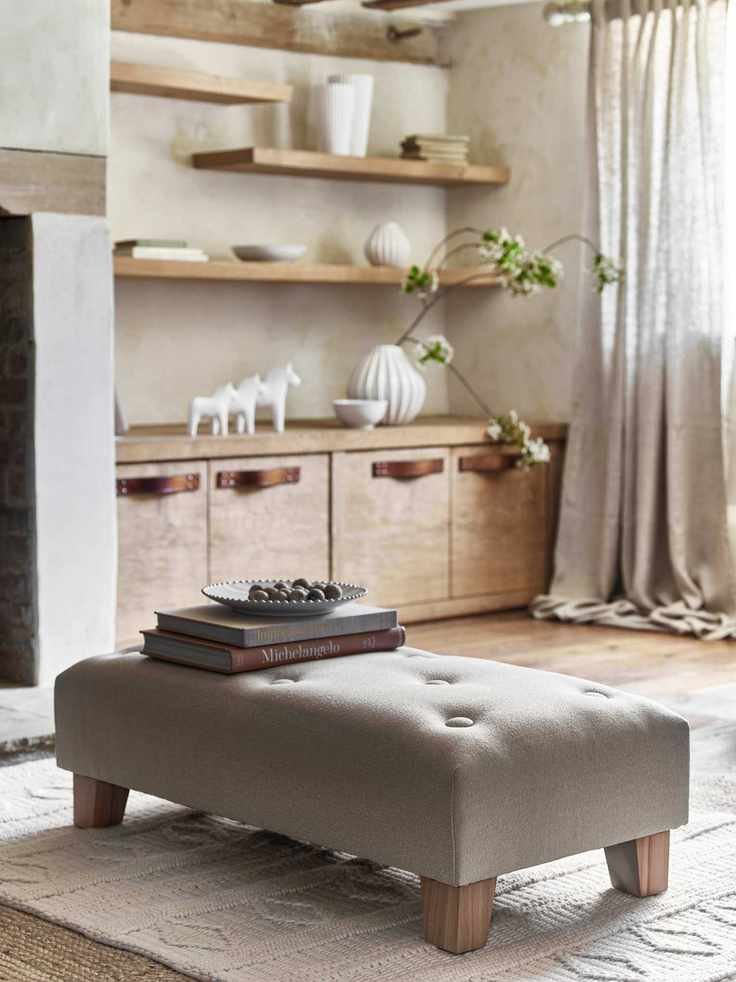 farmhouse living room with ottoman, wooden shelving, cream carpet