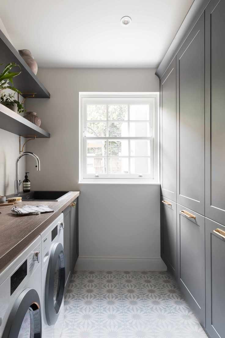 Narrow utility room showcasing grey cabinetry and patterned tile flooring