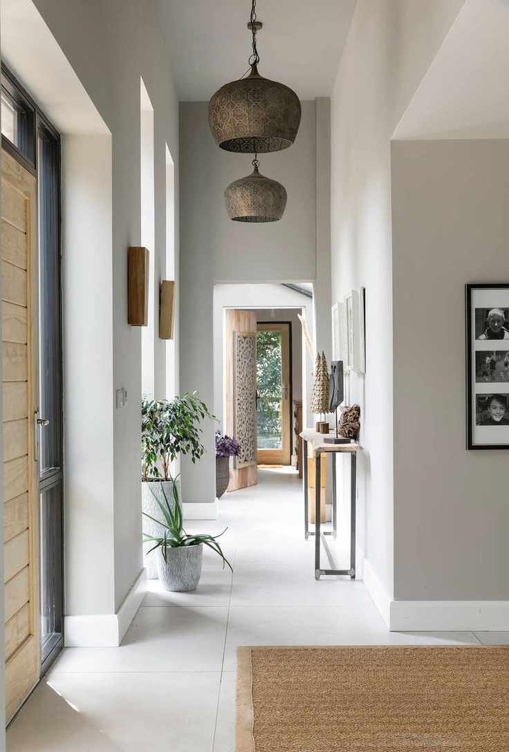 entry way with wooden front door gray green neutral colors and brass pendant lights