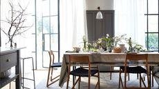 Grey and white dining room with retro chairs and table with tablecloth laid with spring flower displays