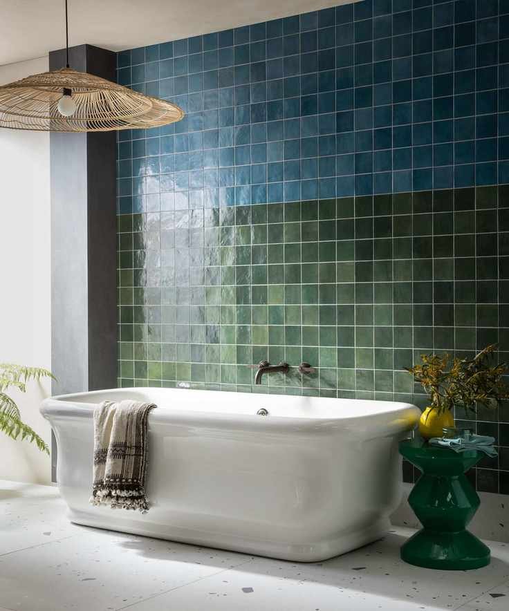 Bathroom with blue and green gloss tiles and a large white bathtub