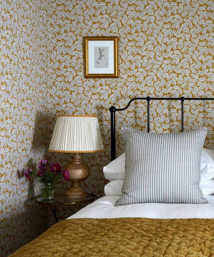 Bedroom with patterned wallpaper, lampshade and bedding