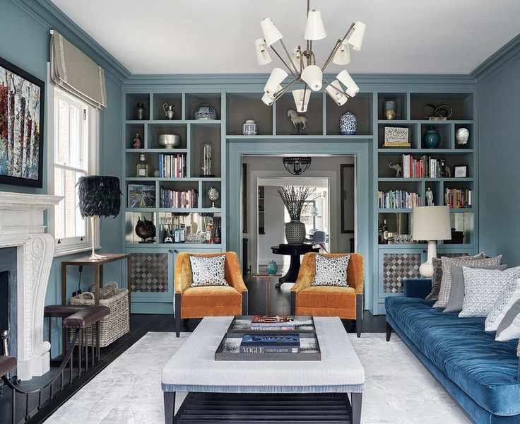 Small living room lighting with blue walls, blue sofa, orange armchairs and a sputnik chandelier with coned lampshades over the bulbs