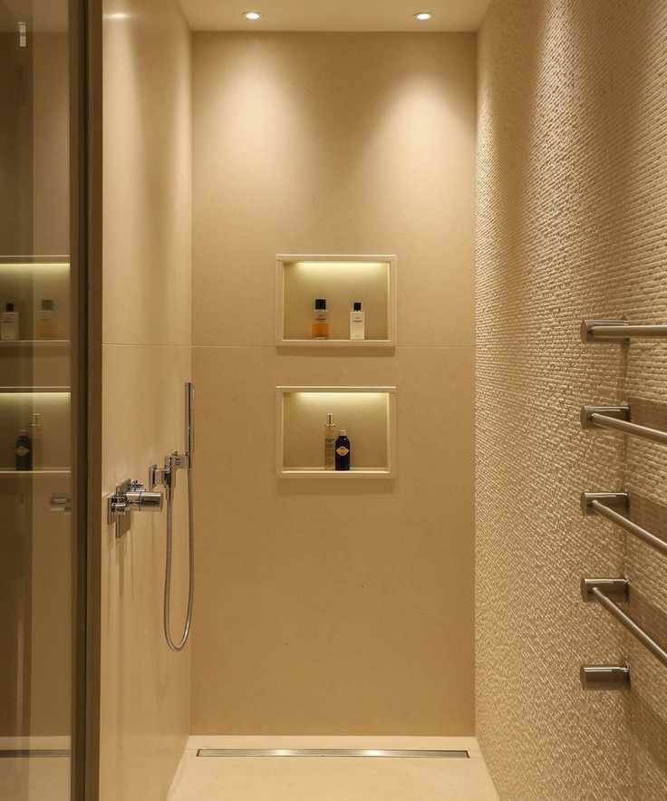 Shower in a bathroom with textured, cream painted wall, two integrated shower niches, four spotlights on ceiling